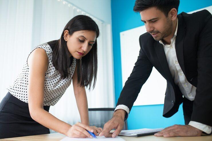 serious young executive checking document with his secretary